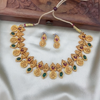 Gold necklace and earrings set on a white fabric with a wooden box in the background
