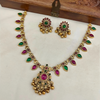 Gold necklace with colorful stones on a white cushion, wooden box in the background