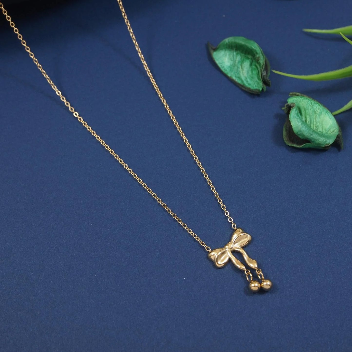 Gold necklace with a bow pendant on a blue background