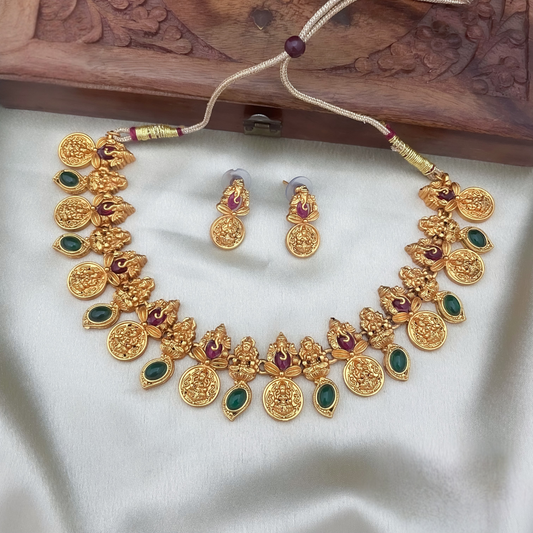 Gold necklace and earrings set on a white fabric with a wooden box in the background