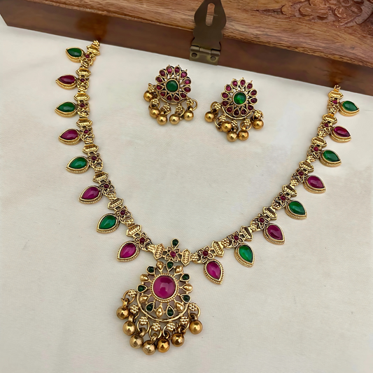 Gold necklace with colorful stones on a white cushion, wooden box in the background